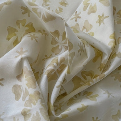 Tela batik flores y mariposas dorado suave sobre crema