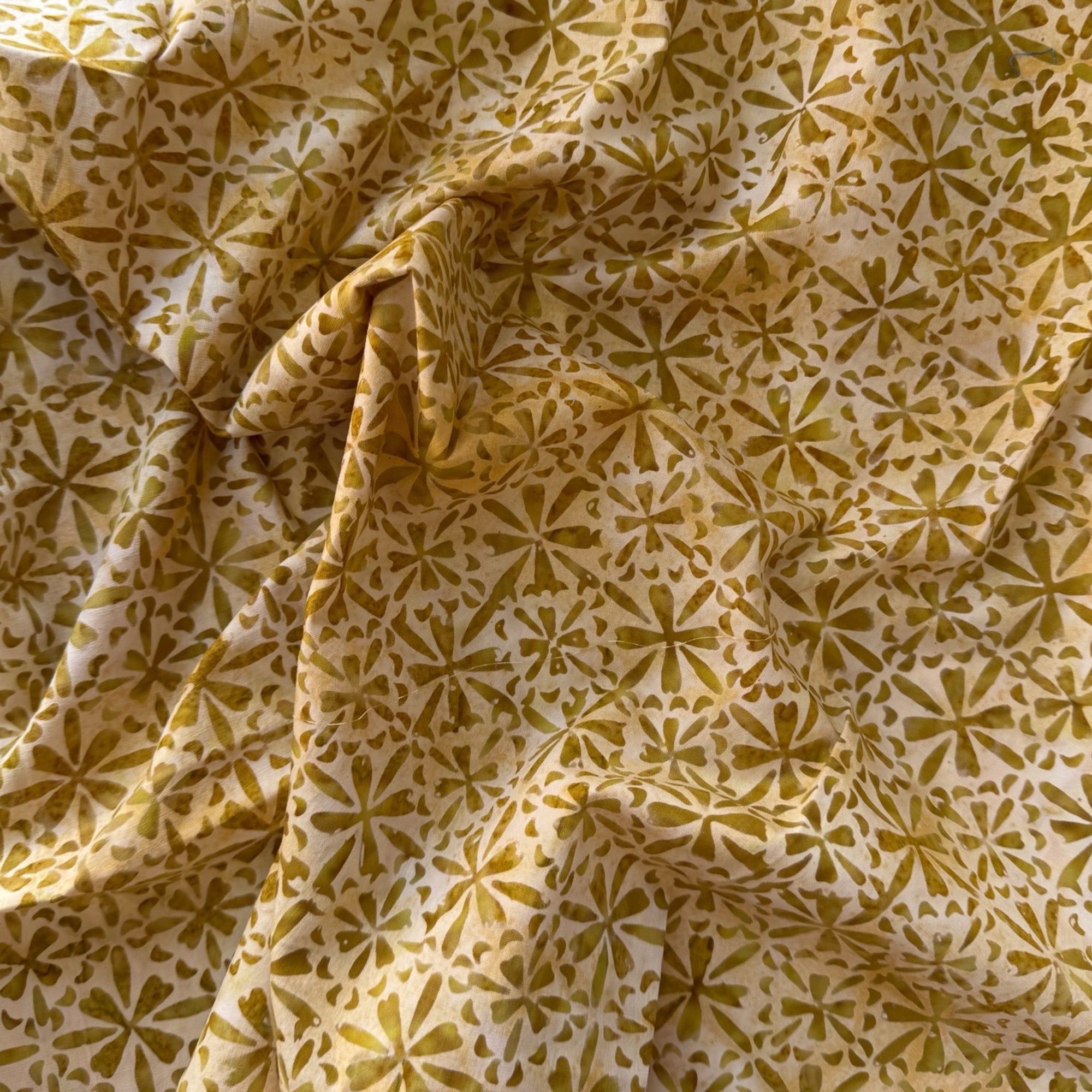 Tela batik estrellas oliva sobre crema